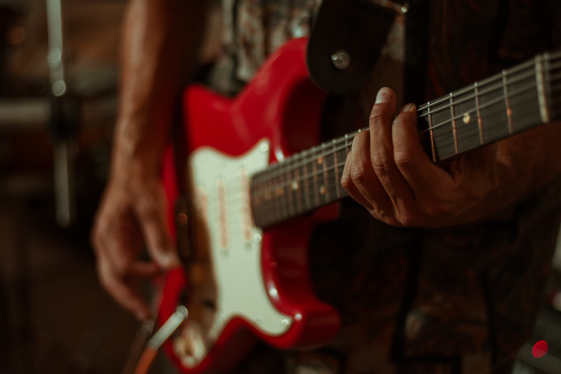 Mãos tocando uma guitarra vermelha durante a passagem de som
